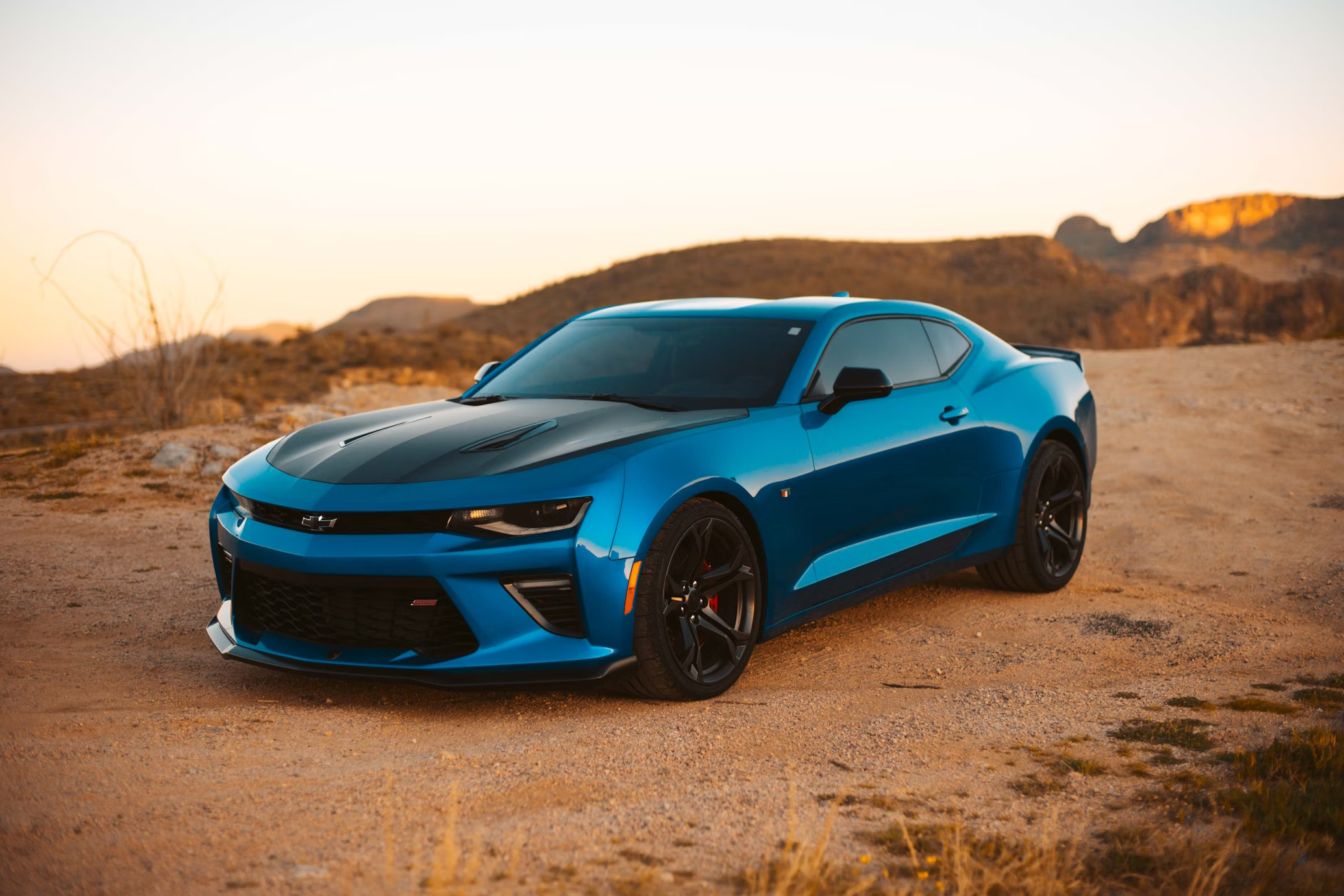 A blue sports car parked in a desert landscape